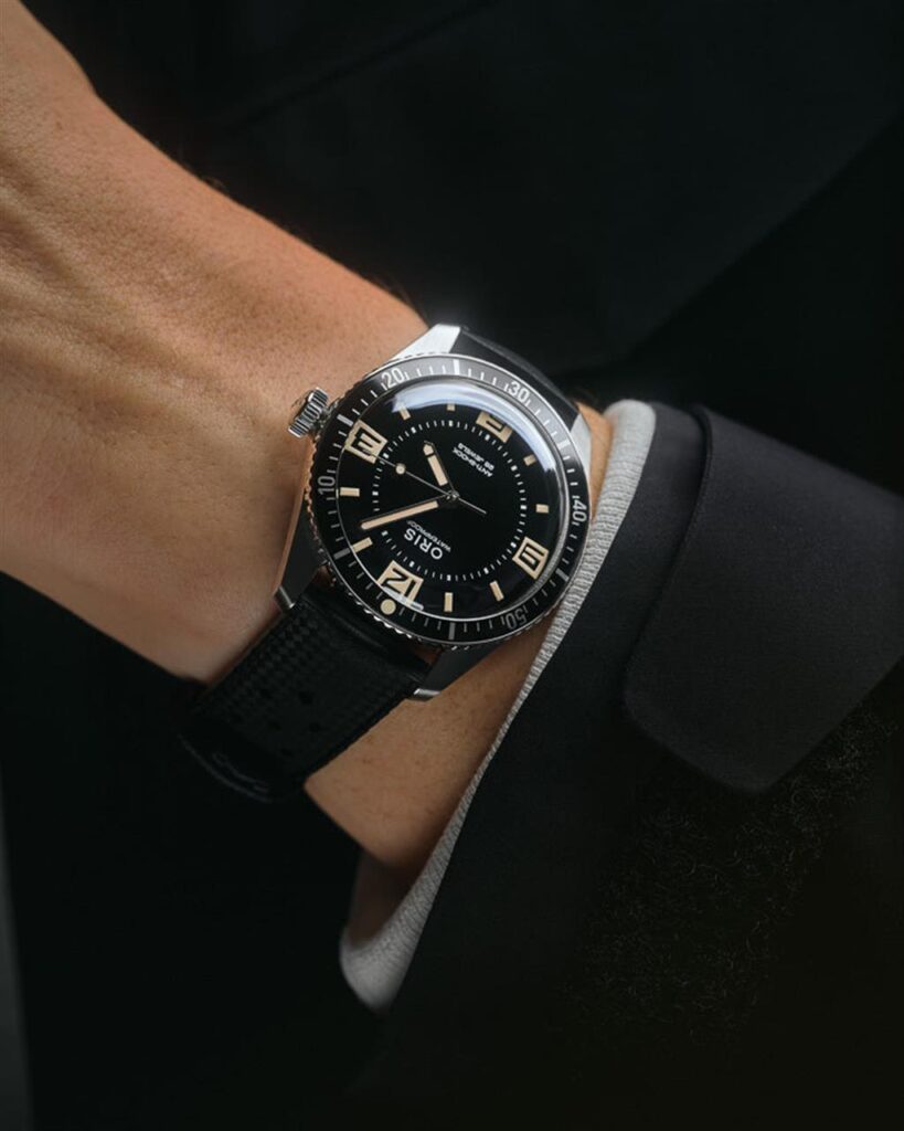 Sleek divers watch on a wrist, featuring a black dial, luminescent markers, and rubber strap.
