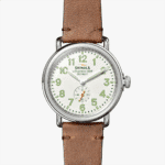 Shinola wristwatch featuring a stainless steel case, white dial, and brown leather strap.
