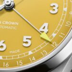 Vibrant yellow automatic watch face with silver hands, bold markers, and Swiss craftsmanship.