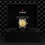 Elegantly presented Tudor watch with gold dial and green strap in a luxurious display box.