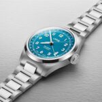 Teal Oris wristwatch with stainless steel case and bracelet, featuring large Arabic numerals.