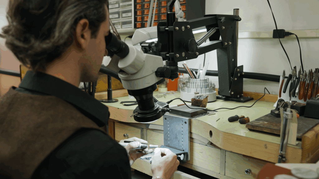 Craftsman using a microscope in a well-organized workshop for precision detailing and craftsmanship.
