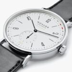 Elegant NOMOS Glashütte watch with minimalist design, white dial, and black leather strap.
