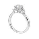 Elegant engagement ring featuring a round diamond and marquise side stones in white metal.
