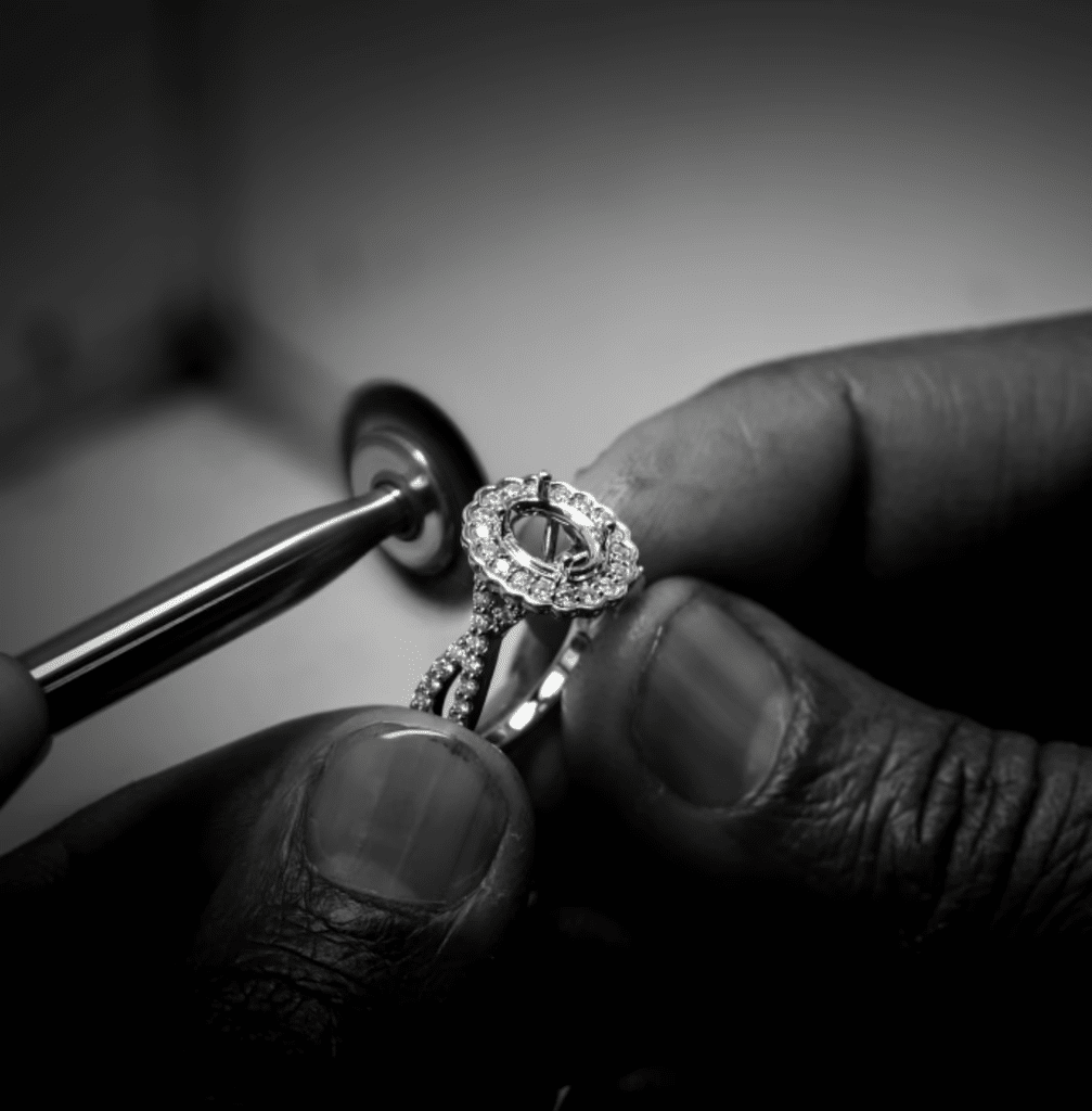 Skilled artisan polishing an exquisite engagement ring with diamonds in a jewelry workshop.