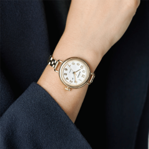 Elegant gold and black watch on wrist, showcasing sophisticated design against dark fabric backdrop.