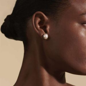 Elegant close-up portrait featuring a graceful profile, pearl earring, and soft warm lighting.