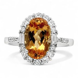 Elegant golden-orange gemstone ring with diamond halo in polished white gold band.