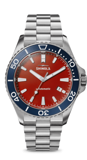 Shinola automatic watch featuring a bold red dial, stainless steel case, and blue rotating bezel.