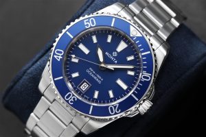 Sophisticated diving watch on blue cushion, featuring a luminous blue dial and stainless steel bracelet.