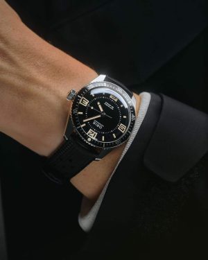 Sleek divers watch on a wrist, featuring a black dial, luminescent markers, and rubber strap.