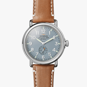 Elegant Shinola wristwatch with light blue dial, Arabic numerals, and brown leather strap.