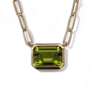 Elegant gold necklace featuring a vibrant emerald-cut peridot gemstone pendant.