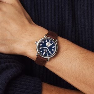 Stylish blue dial watch with leather strap showcased on a groomed wrist.