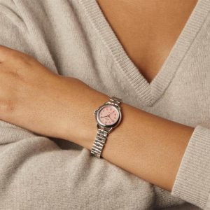 Stylish pink dial watch on a wrist with a cozy gray sweater, showcasing elegant fashion.