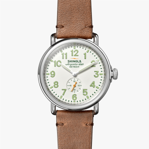 Shinola wristwatch featuring a stainless steel case, white dial, and brown leather strap.