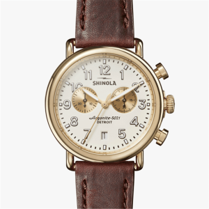 Elegant Shinola wristwatch with gold casing, white dial, and brown leather strap.
