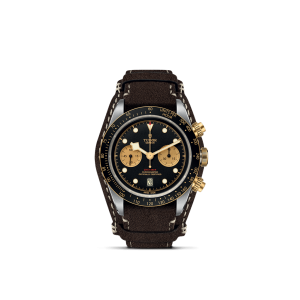 Tudor luxury watch with black dial, gold accents, chronograph features, and brown suede strap.