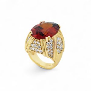 Stunning red gemstone ring in yellow gold with diamond accents, perfect for elegant occasions.