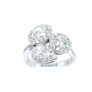 Elegant three-stone diamond ring in white metal, featuring round and pear-shaped gemstones, perfect for engagement.
