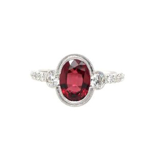 Exquisite red gemstone ring with diamonds, elegant milgrain details, and a luxurious white metal band.