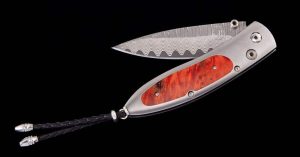 Luxurious damascus steel folding knife with polished wooden handle and decorative leather lanyard.