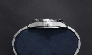 Sleek stainless-steel watch on a plush velvet cushion against a black backdrop.