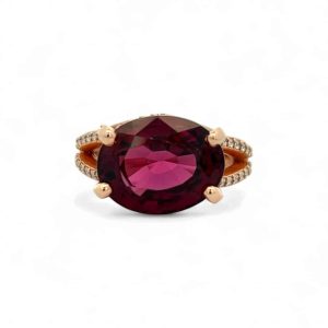 Elegant rose gold ring featuring a central burgundy gemstone and sparkling accents for luxury.
