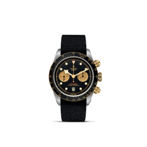 Tudor chronograph watch features a black dial, gold accents, and a textured black strap.